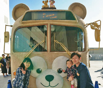 テーマーパークの熊型バスの前で家族と記念写真